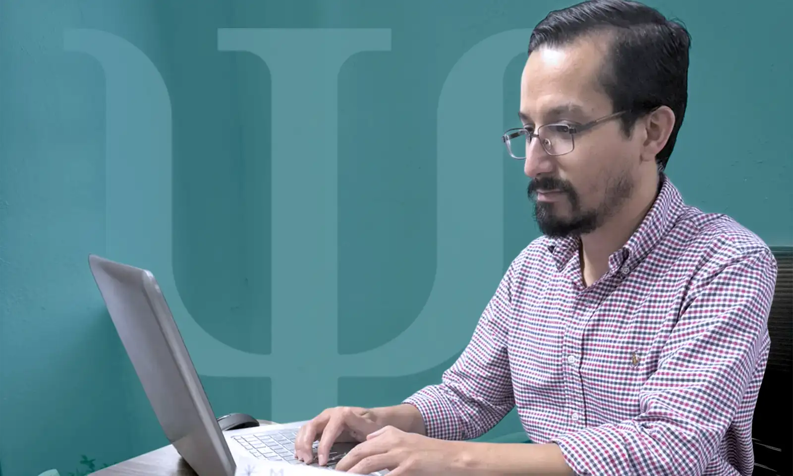 Marco Guajardo psicólogo trabajando en su computadora, comprometido con el bienestar de sus pacientes